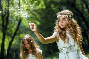 Girl waving magic wand in woods.